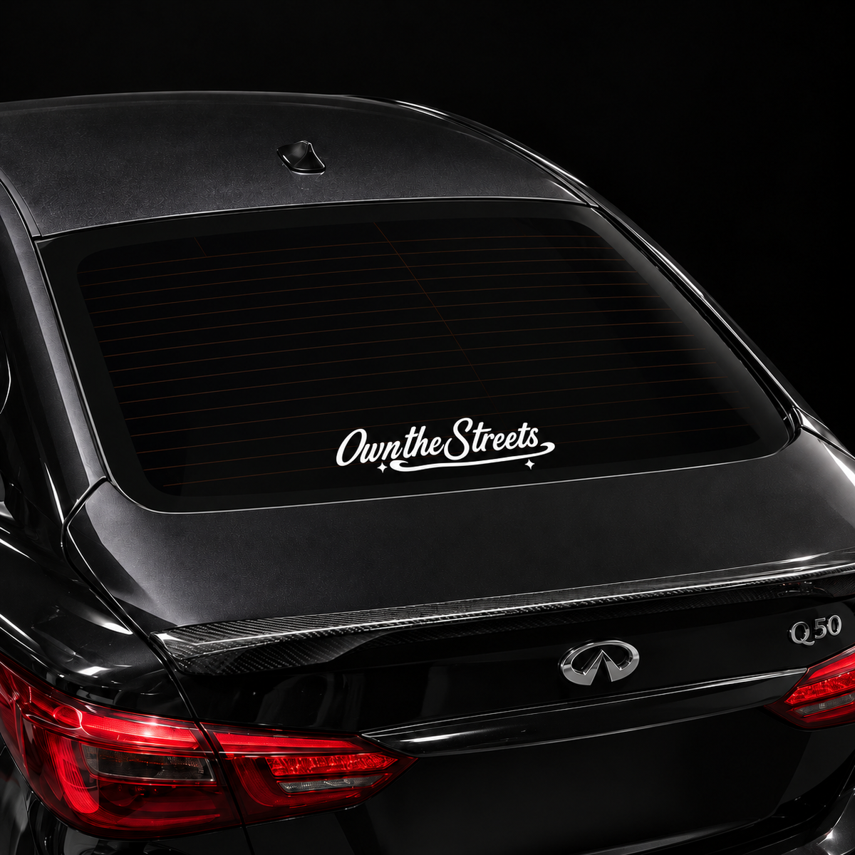White Own the Streets 10 x 2 inch script sticker centered on a black car rear windshield